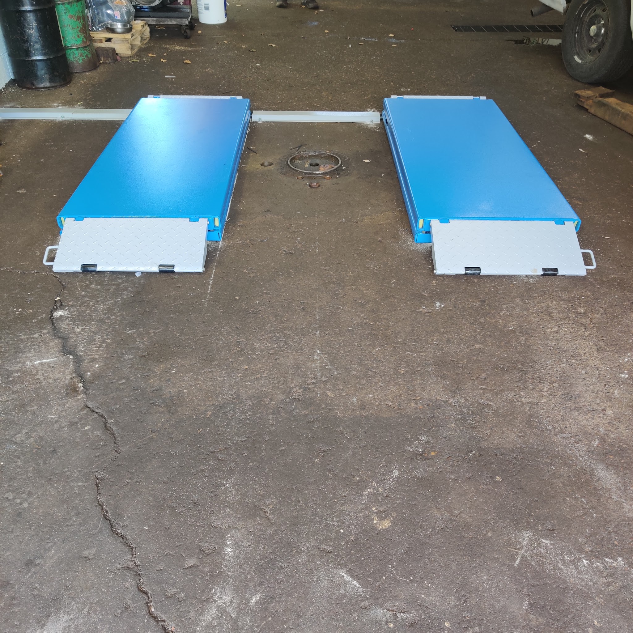 Two blue lift pads with diamond-plate ramps set into the concrete floor of the Remington service bay